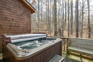 Una vasca idromassaggio su un pontile in legno con vista su una foresta.