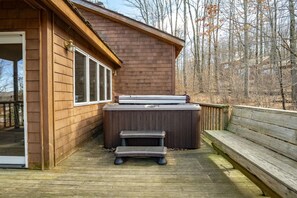 Un patio in legno con una vasca idromassaggio e scale che conducono a una zona coperta.