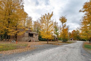 A rustic cabin with a wooden exterior, a covered porch, and a gravel driveway.