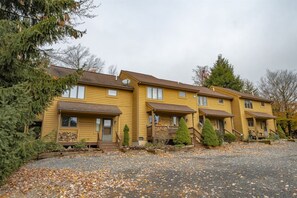 A row of yellow buildings with multiple windows and a gravel driveway.