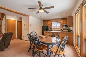A dining area with a round table and chairs, a ceiling fan, and wooden cabinets.