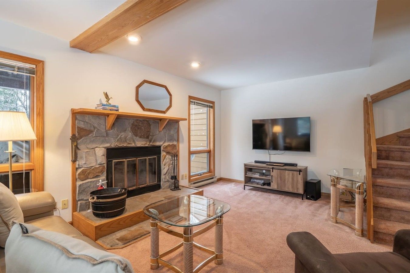 Una sala de estar con chimenea de piedra, un televisor de pantalla plana y una escalera.