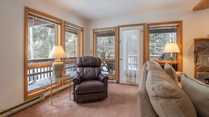 A cozy living room with a leather armchair, a beige sofa, and a fireplace. - Deerfield Village 099 (Davis)