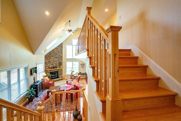 A spacious living area with a fireplace, comfortable seating, and a wooden staircase.