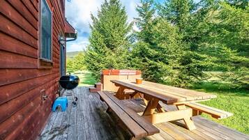 Une terrasse en bois avec des tables de pique-nique et un barbecue.
