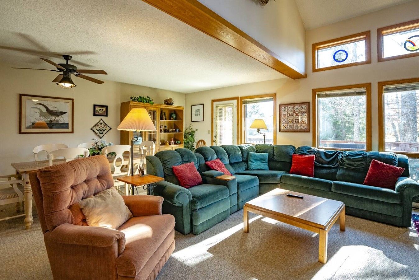 A living room with a sectional sofa, a coffee table, and a ceiling fan.