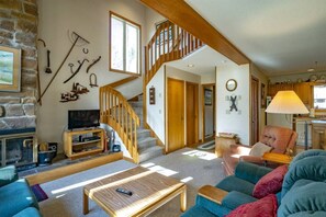 A cozy living room with a fireplace, a wooden staircase, and a kitchen area. - Deerfield Village 40 - Community Pool and Tennis C (Davis)