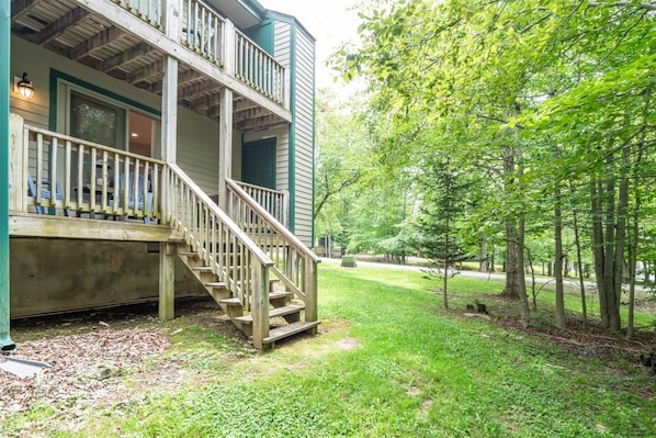 A two-story house with a wooden deck and a staircase leading to the entrance.