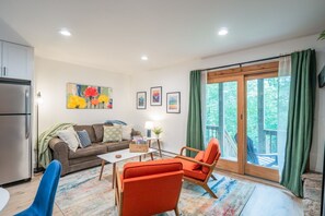 En stue med sofa, lænestole, sofabord og kunst på væggen.