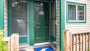 Puerta verde con un letrero de bienvenida para un retiro, un buzón y una valla de madera.