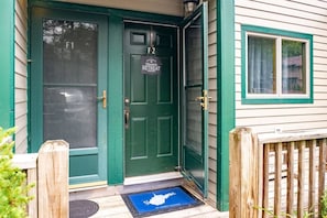 A green door with a welcome sign for a retreat, a mailbox, and a wooden fence.