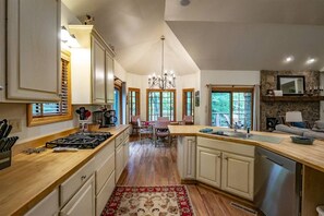 A spacious kitchen with wooden countertops, a central island, and a dining area with chairs.