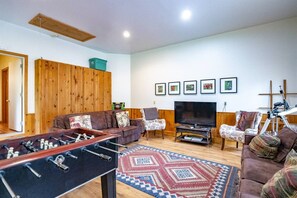 A living room with a foosball table, a sofa, a television, and a telescope.