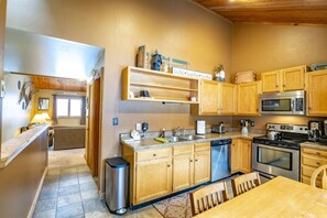 A compact kitchen with wooden cabinets, a stainless steel dishwasher, a microwave, and a stove. - Northwoods B5 - Ski-in/Ski-out at Timberline (Davis)