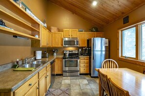 A compact kitchen with wooden cabinets, stainless steel appliances, and a window providing natural light.