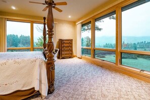 A bedroom with a large window, a wooden bed, and a dresser.