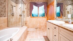 Un baño con ducha envuelta en vidrio, bañera, tocador con lavamanos y ventana con cortinas.