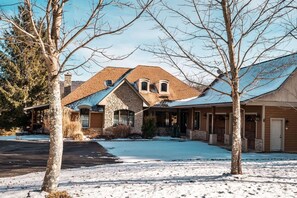 A residential property with a stone facade, a covered porch, and a snow-covered driveway.