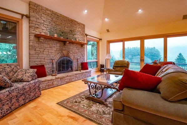 Un salón acogedor con chimenea de piedra, ventanas amplias y asientos cómodos.