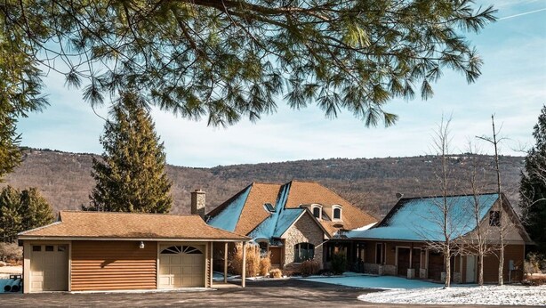 Una casa de dos pisos con garaje, un porche cubierto y una piscina.
