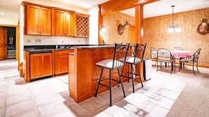 Una cocina con armarios de madera, una isla central y una zona de comedor con sillas de metal y una mesa.