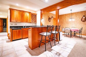 A kitchen with wooden cabinets, a central island, and a dining area with metal chairs and a table.