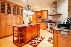 A kitchen with wooden cabinets, a central island, a stove, and a microwave. - Deer Walk - Private Pond, Access to Dolly Sods (Davis)