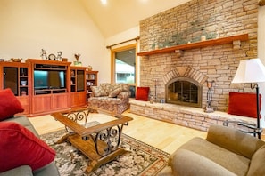 Una sala de estar con chimenea de piedra, televisor y sofá.