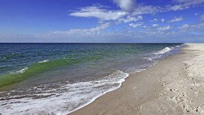 Une plage avec une eau d’un bleu limpide et un rivage sablonneux.