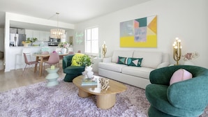 Un salon moderne comprenant un canapé, des fauteuils, une table basse et un coin repas avec des chaises et une table.