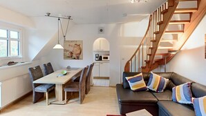Un intérieur moderne comprenant un coin repas, une cuisine et un escalier.