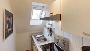 Une petite cuisine équipée d’une fenêtre, d’un évier et d’un plan de travail avec des ustensiles.