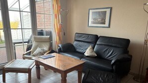 Ein Wohnzimmer mit einer schwarzen Ledersofa, einem Holztisch und einem gepolsterten Sessel.
