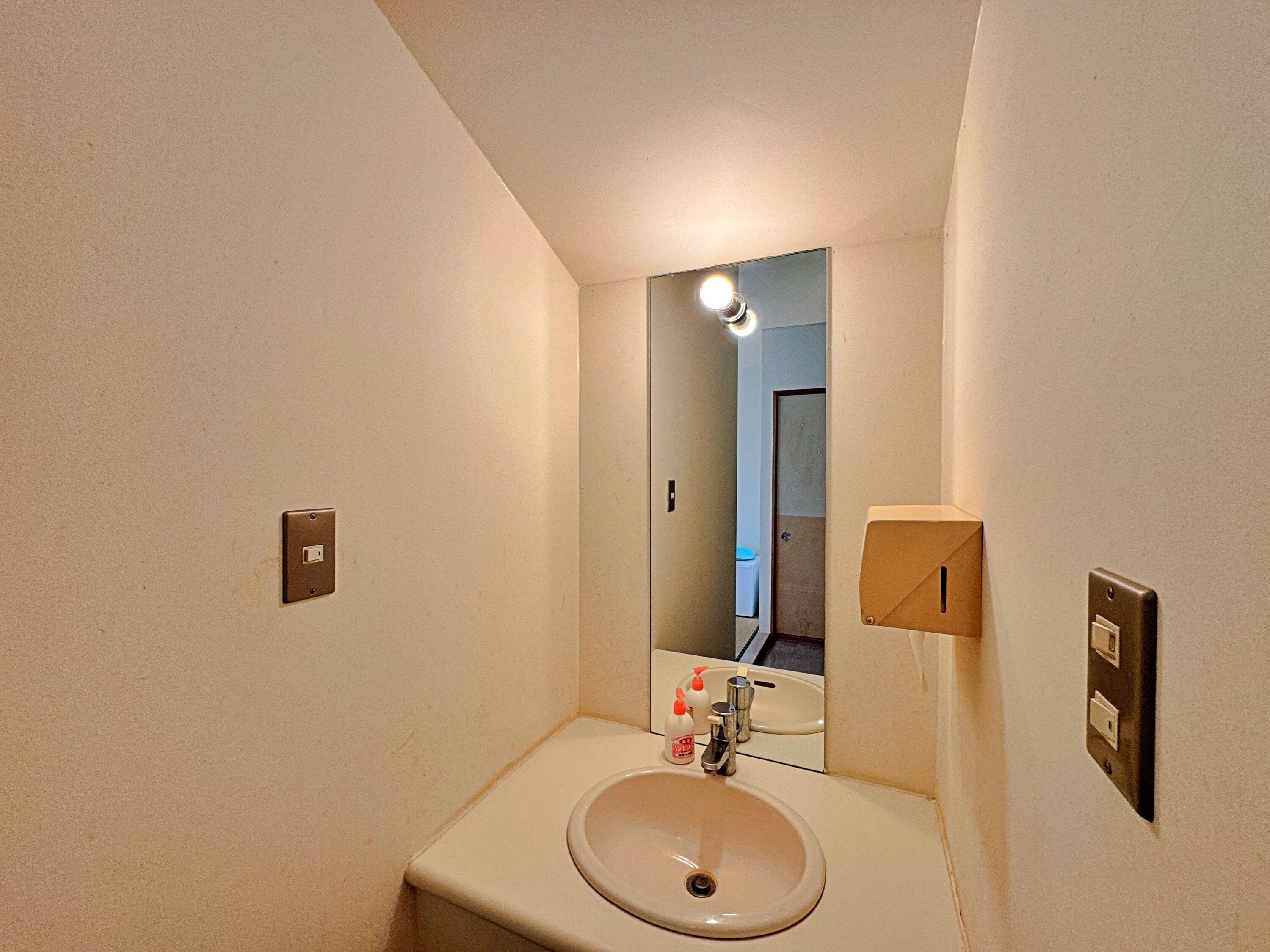 A bathroom with a sink, mirror, and two light switches on the wall.