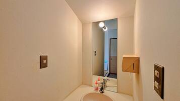 A bathroom with a sink, mirror, and two light switches on the wall.