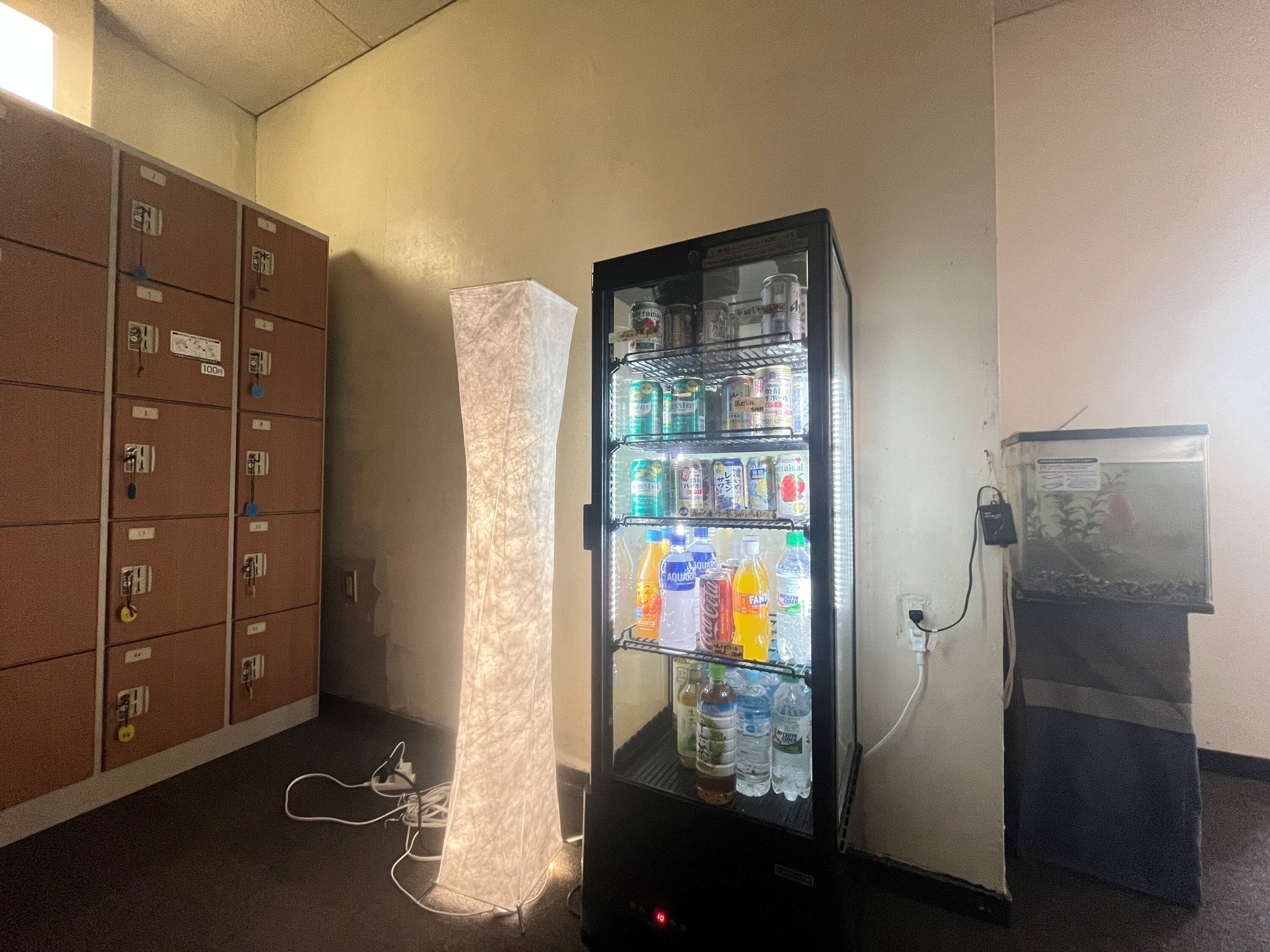 Máquina expendedora con bebidas, armario de servicios con cajones etiquetados y dispensador de agua.