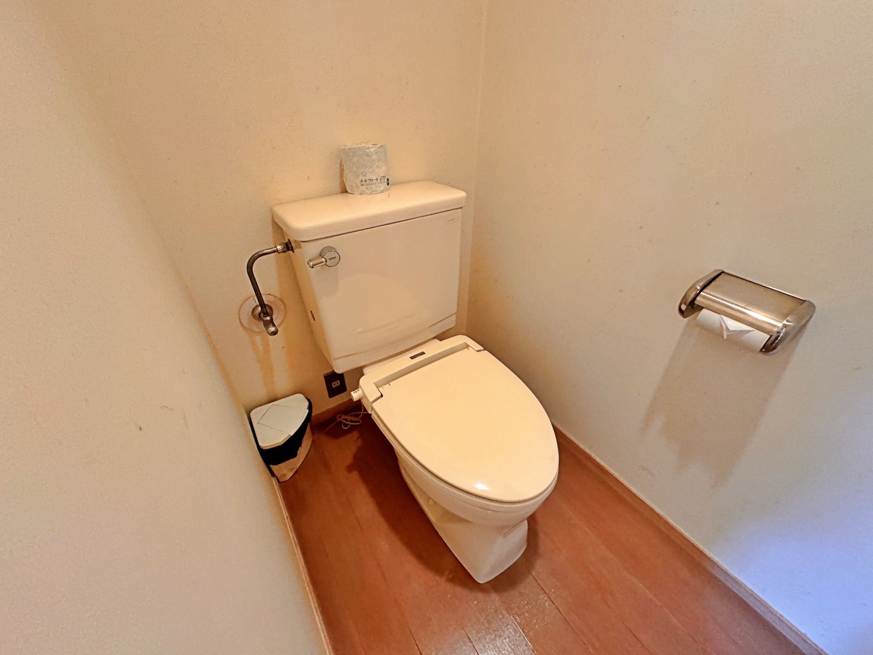 A small, compact bathroom with a white toilet, a bidet, and a toilet paper holder on the wall.