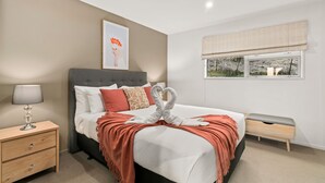 A neatly arranged bedroom with a bed, bedside table, and a window with a view. - 2-BEDROOM REMARKABLES APARTMENT (Queenstown)