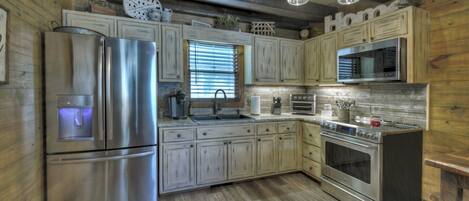 A modern kitchen with stainless steel appliances, wooden cabinets, and a farmhouse aesthetic.