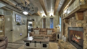 Un salon chaleureux avec une cheminée, un ventilateur de plafond et un mur décoratif en pierre.