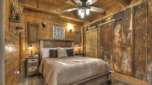 Une chambre à coucher au style rustique, avec un plafond en bois, un lit doté d’une tête de lit et une grande armoire.
