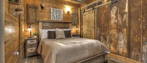 A rustic bedroom with a wooden ceiling, a bed with a headboard, and a large wardrobe.