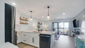 Una cucina moderna con mobili bianchi, elettrodomestici in acciaio inossidabile e luci a sospensione.
