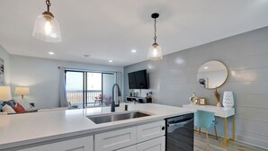 Una cucina moderna con un'isola grande, mobili bianchi e un'lavastoviglie nera.