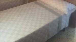 Une chambre avec deux lits simples, chacun étant équipé d’un oreiller et d’une couverture.