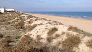 Une plage avec des dunes de sable et un bâtiment en arrière-plan.
