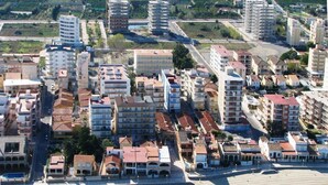 Vue aérienne d’une ville côtière caractérisée par une urbanisation dense, avec de nombreux immeubles et une zone de plage.