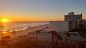 Een hotel met uitzicht op het strand en de oceaan bij zonsondergang.