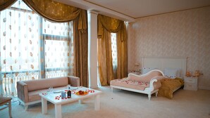 Una habitación con sofá, cama, mesita de noche y una mesa con pétalos de rosa.