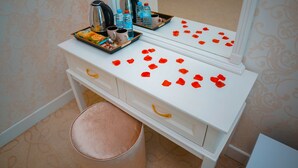 Un tocador de baño con artículos de aseo, un espejo y pétalos de rosa sobre la encimera.